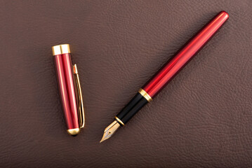 Red fountain pen on leather surface, selective focus