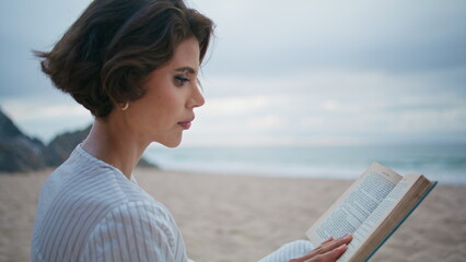 Beautiful woman reading beach on rocky island closeup. Calm girl relax outdoors