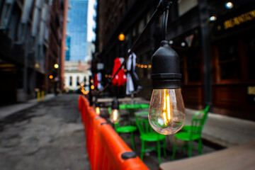 City street with tables, neon lights, and colorful chairs