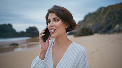 Smiling woman calling beach on cloudy day closeup. Relaxed girl talk smartphone