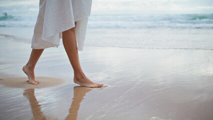 Woman feet stepping sea beach closeup. Slim legs walking ocean shore in summer