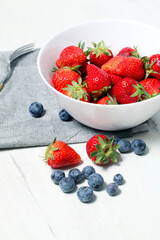 White bowl with fresh seasonal strawberries and blueberries