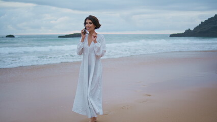 Fototapeta na wymiar Carefree girl speaking smartphone on beautiful ocean beach. Smiling lady calling