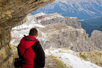Young mountain climber in the Dolomite Mountains Italy. A man with hiking backpack and sticks...