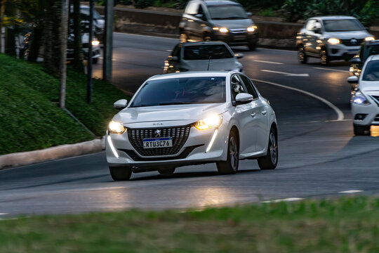 Panning shot of a white Peugeot 208, White hatchback in city traffic