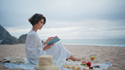 Romantic lady holding book at cloudy seashore. Beautiful reader resting beach
