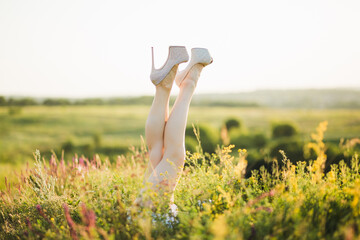 Woman's legs in grass in high-heeled shoes