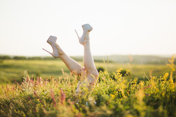 Woman's legs in grass in high-heeled shoes