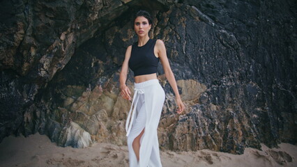 Stylish girl spinning beach at seaside cliffs. Professional fashion model posing
