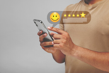 Man leaving service feedback with smartphone on light background, closeup. Stars and emoticon over...