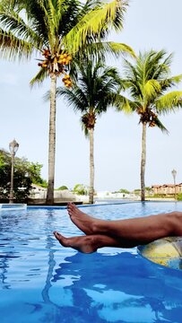 Young woman relaxing inside swimming pool at hotel during summer holiday vacations.