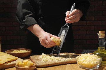 Woman grating cheese at wooden table, closeup