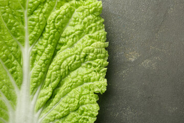 Fresh Chinese cabbage leaf on gray textured table, top view. Space for text