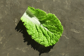 Fresh Chinese cabbage leaf on gray textured table, top view