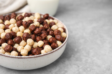 Tasty cereal balls in bowl on grey table, closeup. Space for text