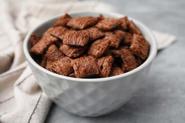Chocolate cereal pads in bowl on grey table, closeup