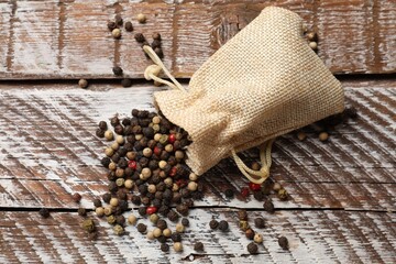 Aromatic spice. Different peppers in burlap bag on wooden table, top view