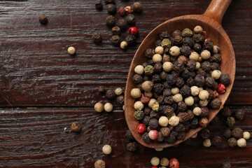 Aromatic spice. Different peppers in spoon on black table, top view. Space for text