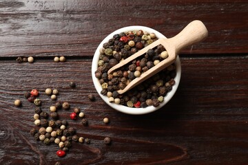 Aromatic spice. Different peppers in bowl and scoop on wooden table, top view