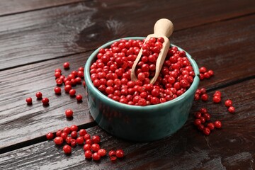 Aromatic spice. Red pepper in bowl and scoop on wooden table, closeup