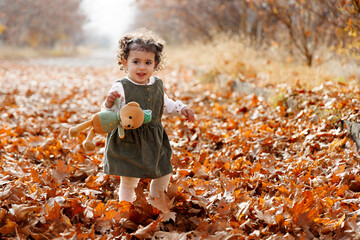 Autumn s gentle caress. Smiling adorable child wandering among golden autumn leaves