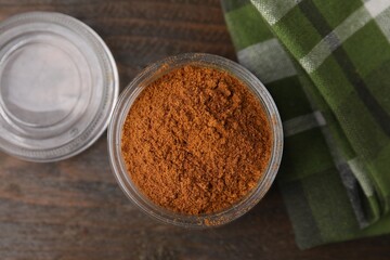 Ground red pepper in jar on wooden table, top view