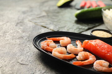 Fresh salmon, shrimps and other ingredients for sushi on dark textured table, closeup. Space for...