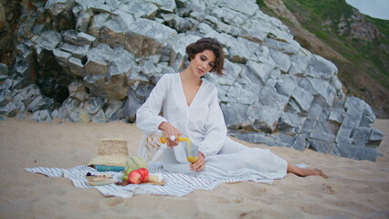 Beach woman drink juice on summer picnic. Romantic girl pouring fresh beverage