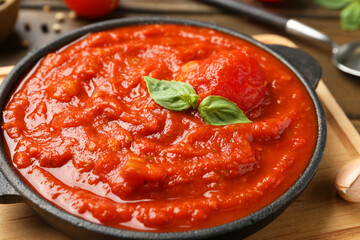 Homemade tomato sauce and basil in bowl on table, closeup
