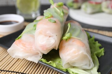 Delicious spring rolls wrapped in rice paper on table, closeup