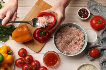 Woman making stuffed peppers with ground meat at white wooden table, top view