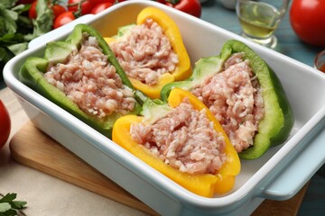 Raw stuffed peppers and ingredients on light blue wooden table, closeup