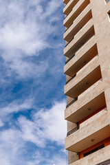 Vertical shot of modern building with balconies against a blue sky, showcasing urban architecture