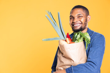 African american satisfied person purchasing organic lettuce and veggies from grocery store, supporting zero waste bio nutrition. Happy man eating fresh local products, delicious groceries.
