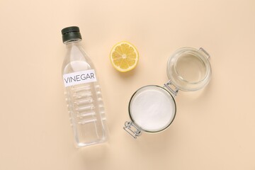 Eco friendly natural cleaners. Vinegar in bottle, cut lemon and jar of soda on beige background, flat lay