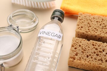 Eco friendly natural cleaners. Vinegar in bottle, jar of soda and sponges on beige background