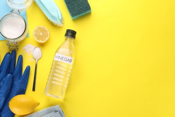 Eco friendly natural cleaners. Flat lay composition with bottle of vinegar on yellow background,...