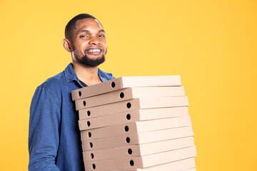 African american courier carrying huge stack of pizza boxes to deliver fast food order to customer,...