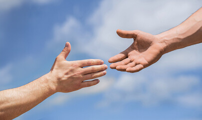 Two male hands reaching towards each other on isolated sky background. Helping hand outstretched,...