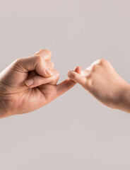 Two hands hook pinky fingers together to promise, swear or asking for reconciled together. Child...