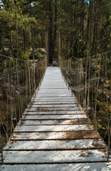 Obraz premium A beautiful wooden suspension bridge covered with snow. Vertical photography