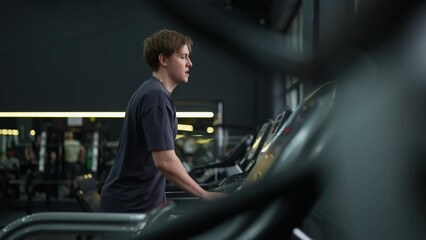 Beginner runner male running on treadmill, finishing exercise and turns off trainer machine. Athletic sportsman resting after intensive cardio workout to burn calories in gym. Shooting in slow motion. - Powered by Adobe