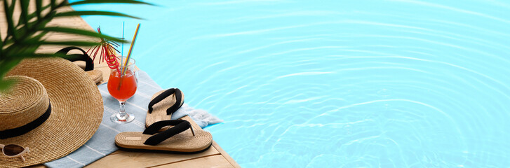 Different beach accessories with plant branches and cocktail on wooden pontoon against blue...