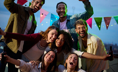 Portrait of excited young diverse people posing for photo at party night. Group happy multiracial...