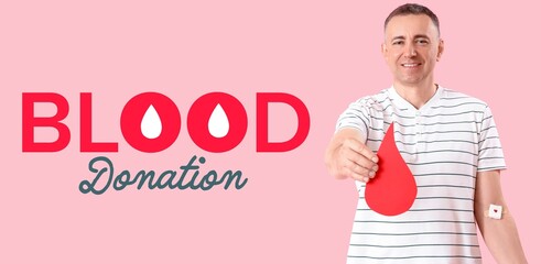 Mature man with paper drop and text BLOOD DONATION on pink background