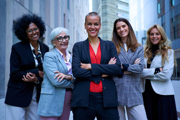 Portrait of multiracial and diverse ages business women in formal suits posing smiling with arms crossed looking at camera. Empowered and successful female entrepreneurs happy and powerful outdoor