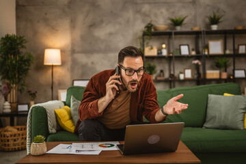 Adult angry man work from home on laptop and yell on mobile phone