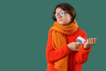 Sick little girl with infrared thermometer on green background