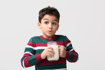 Shocked little boy with mason jar of milk on white background
