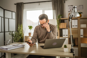 Adult man work at office on laptop and use mobile phone for message